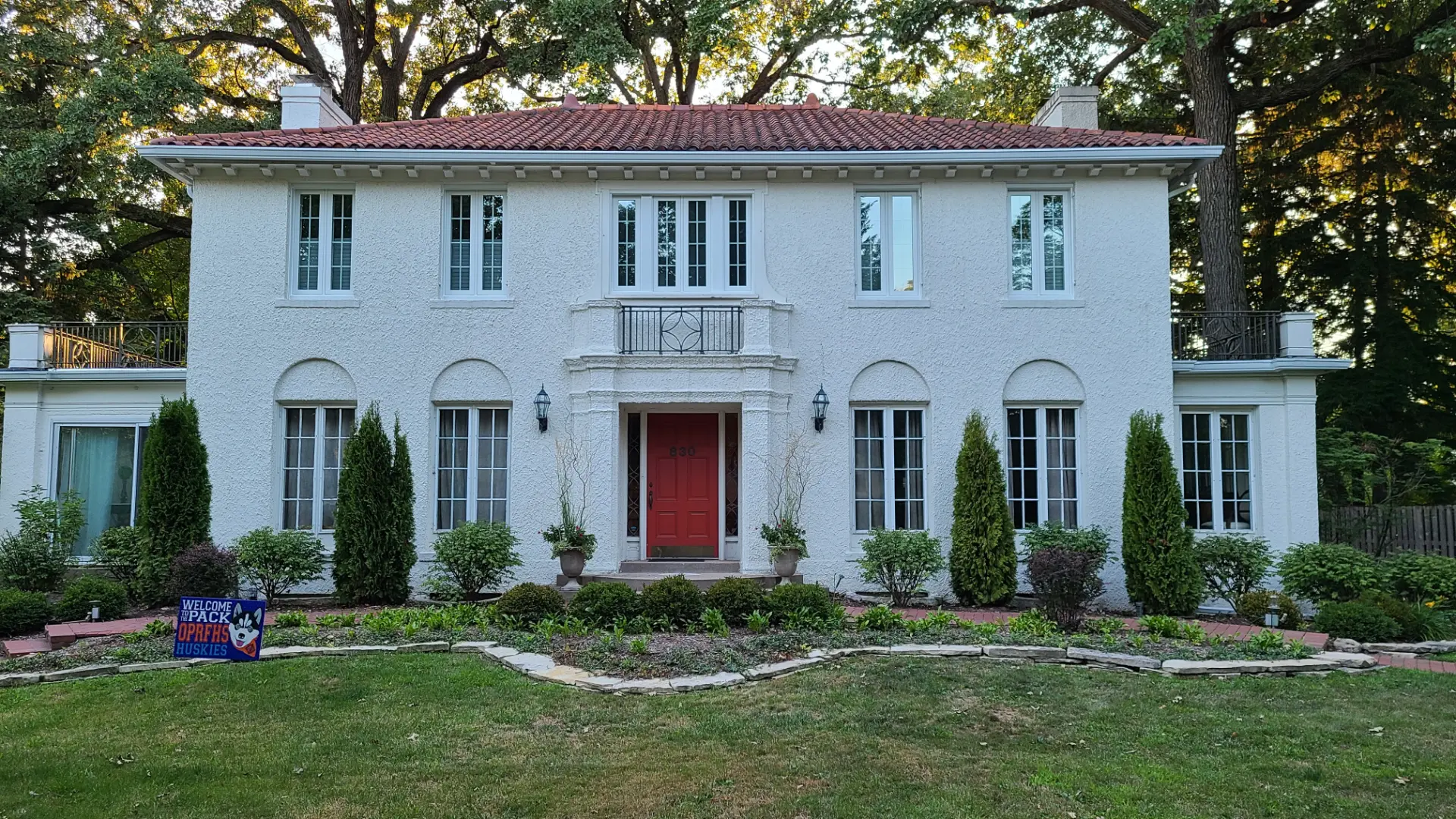 White stucco Mediterranean-style home with replacement windows and a red entry door in Elmhurst, Illinois