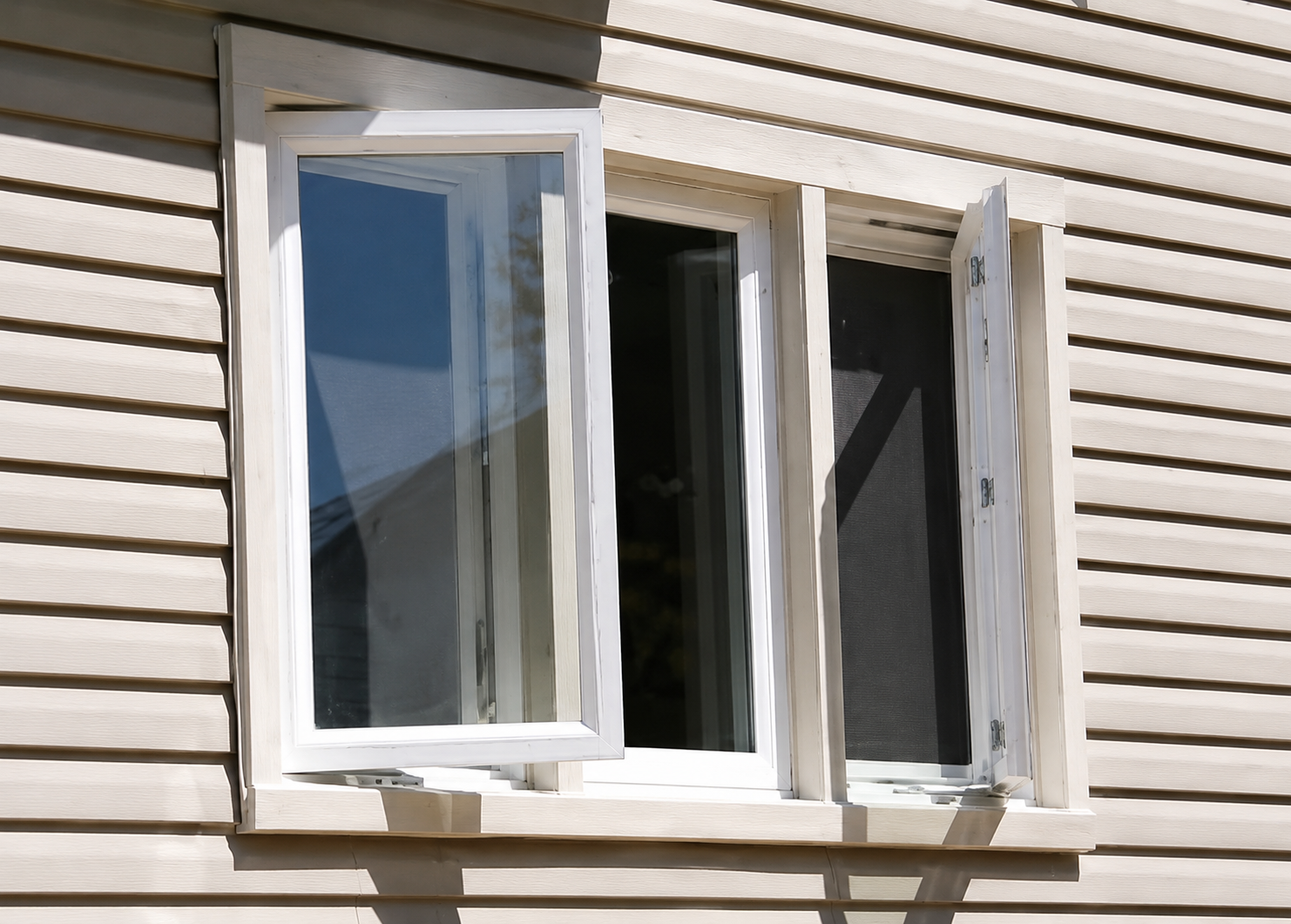 White casement windows with one sash cranked open on beige siding in Elmhurst, Illinois